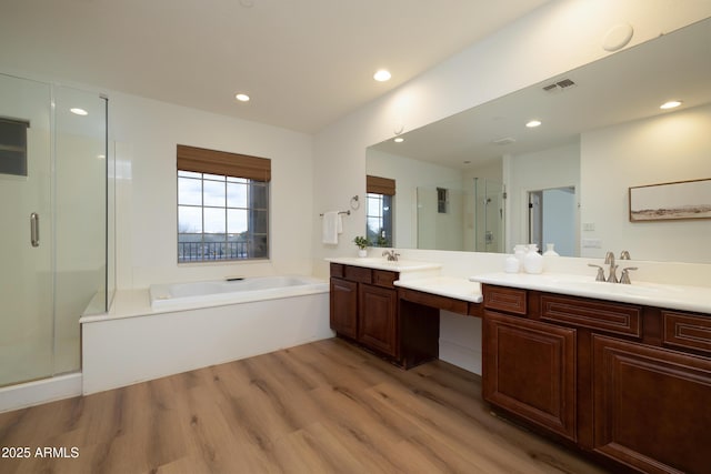 bathroom with visible vents, a garden tub, wood finished floors, a shower stall, and vanity