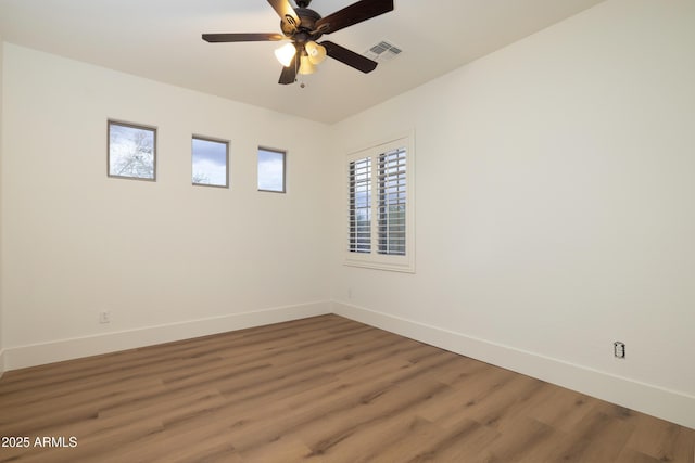 empty room featuring visible vents, light wood-style flooring, a ceiling fan, and baseboards