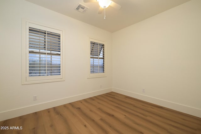 unfurnished room featuring visible vents, baseboards, wood finished floors, and a ceiling fan