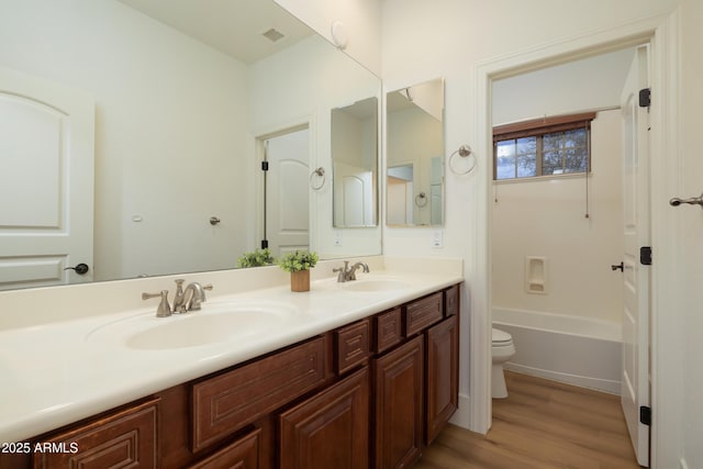 bathroom with double vanity, visible vents, toilet, and a sink