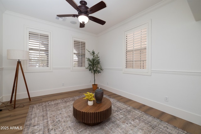 sitting room featuring visible vents, baseboards, ornamental molding, wood finished floors, and a ceiling fan