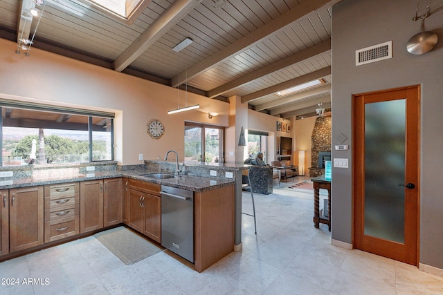 kitchen featuring dark stone countertops, a breakfast bar, kitchen peninsula, dishwasher, and sink