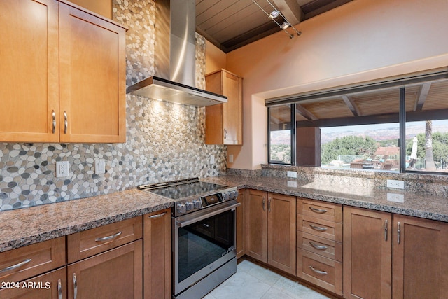 kitchen with stainless steel range with electric cooktop, wall chimney exhaust hood, plenty of natural light, and stone countertops