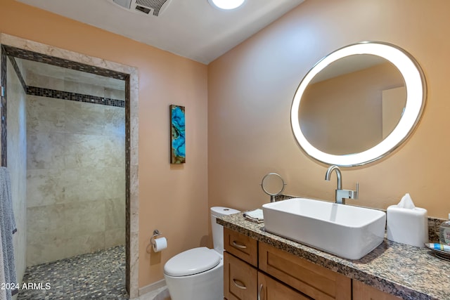 bathroom with tiled shower, vanity, and toilet