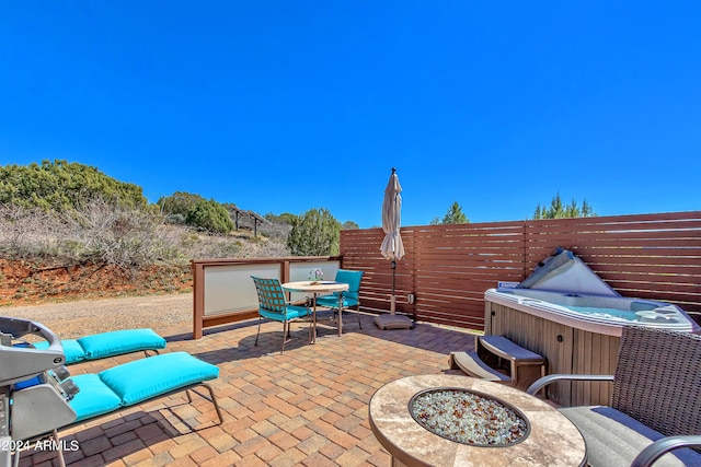 view of patio with an outdoor fire pit and a hot tub