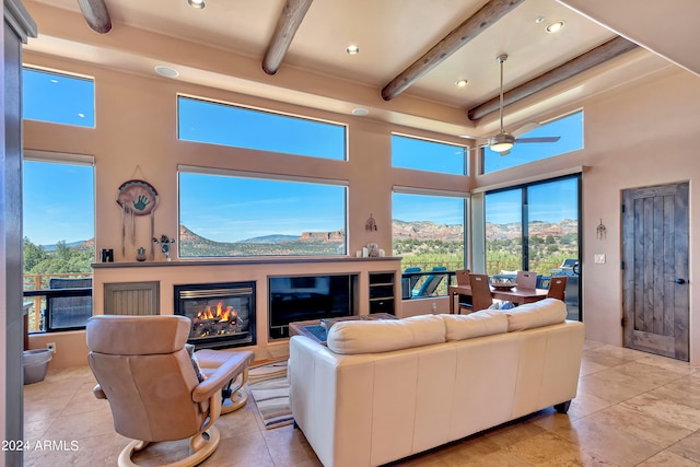 living room featuring a high ceiling, ceiling fan, beamed ceiling, and a mountain view