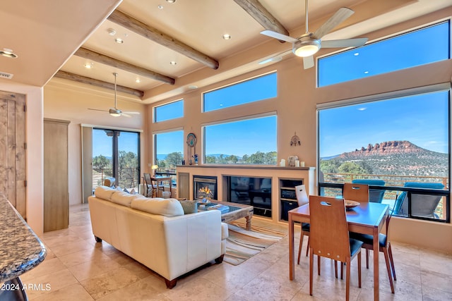 living room with beam ceiling, a towering ceiling, a mountain view, and ceiling fan