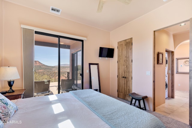 bedroom with access to outside, light tile patterned floors, ceiling fan, and stacked washer and clothes dryer