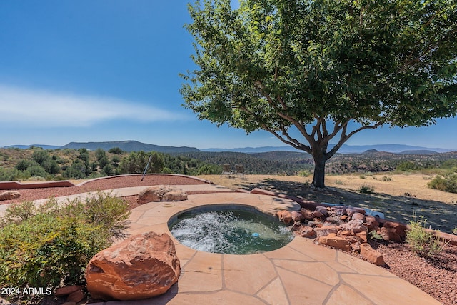 view of patio with an in ground hot tub and a mountain view