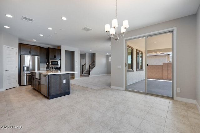 12219 W Caraveo Pl, Peoria, AZ 85383 - kitchen featuring appliances with stainless steel finishes, light countertops, dark brown cabinets, open floor plan, and a chandelier