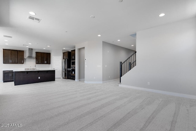 12219 W Caraveo Pl, Peoria, AZ 85383 - unfurnished living room featuring light colored carpet, a sink, recessed lighting, baseboards, and stairway