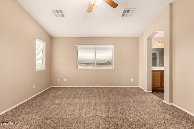 empty room with carpet floors, visible vents, baseboards, and a ceiling fan