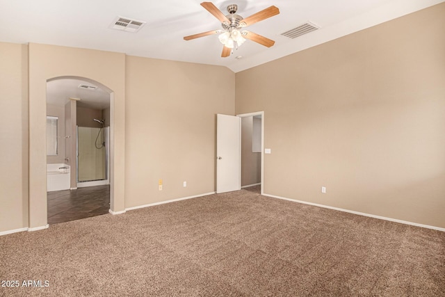 spare room with carpet floors, vaulted ceiling, visible vents, and arched walkways