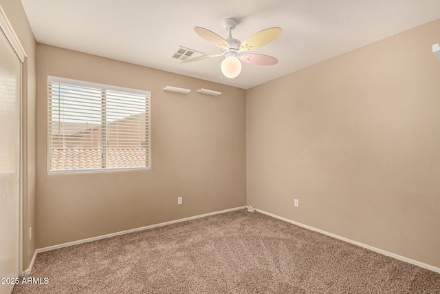 carpeted spare room featuring ceiling fan, visible vents, and baseboards