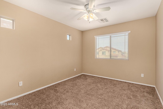 carpeted empty room with ceiling fan, visible vents, and baseboards