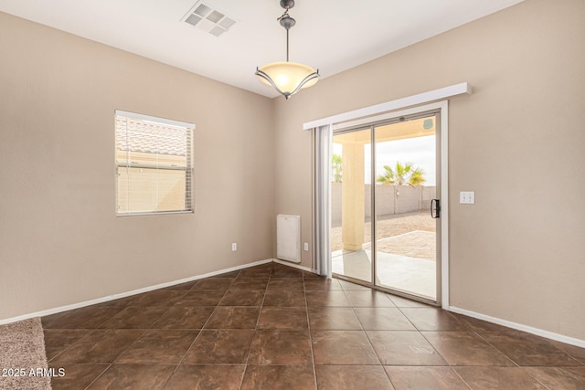 spare room with dark tile patterned floors, visible vents, and baseboards