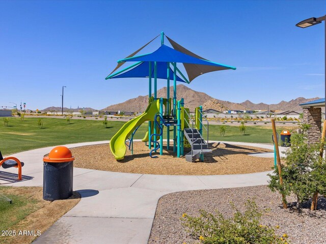 community jungle gym featuring a mountain view and a lawn