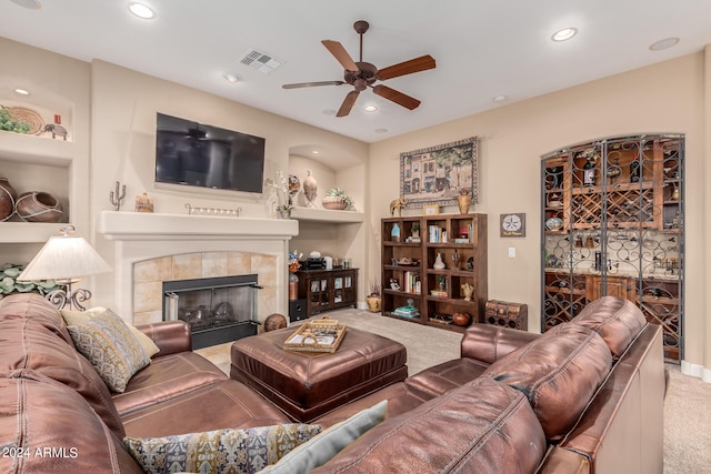 carpeted living room featuring ceiling fan, built in features, and a tile fireplace