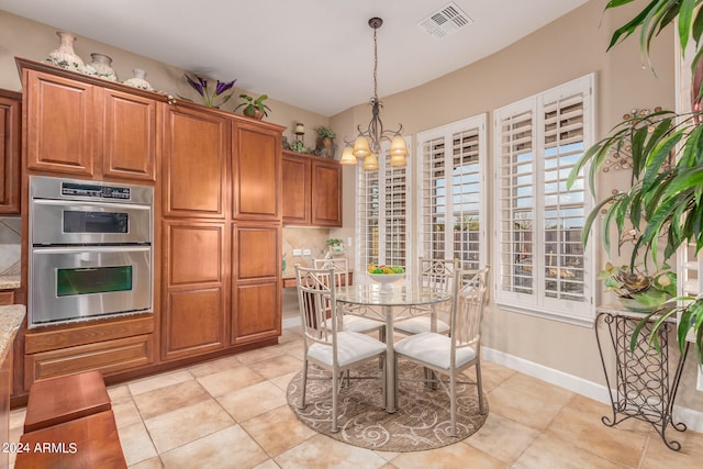 kitchen featuring pendant lighting, a chandelier, light tile patterned flooring, light stone countertops, and double oven