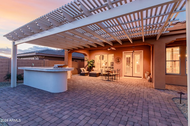 patio terrace at dusk with a pergola, an outdoor living space, exterior bar, and french doors