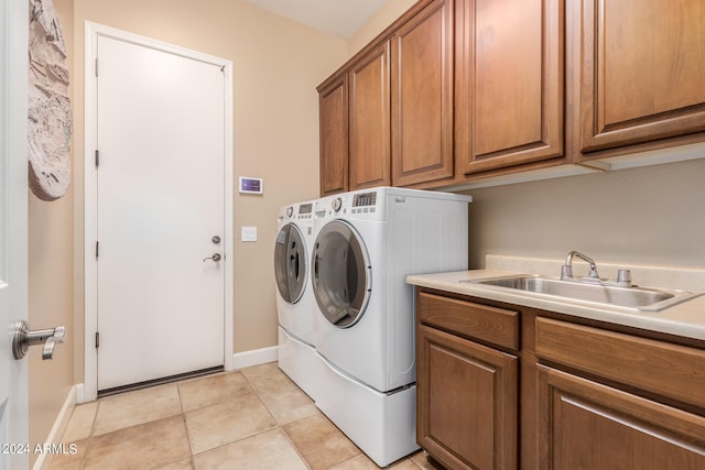 washroom featuring washing machine and dryer, sink, light tile patterned floors, and cabinets