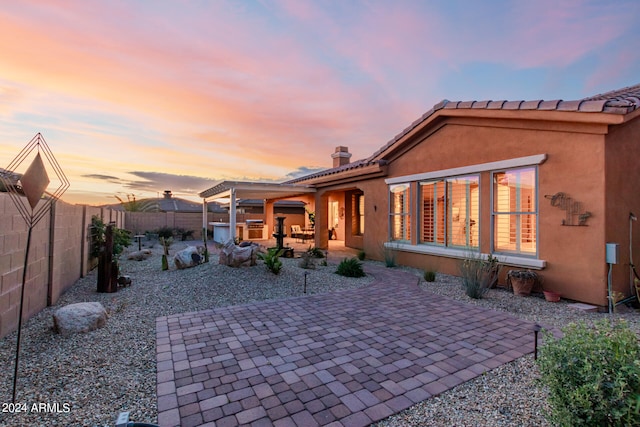 back house at dusk featuring a patio area