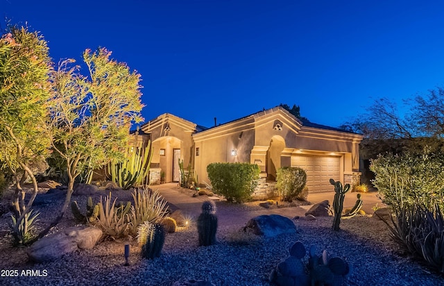 mediterranean / spanish home featuring an attached garage and stucco siding