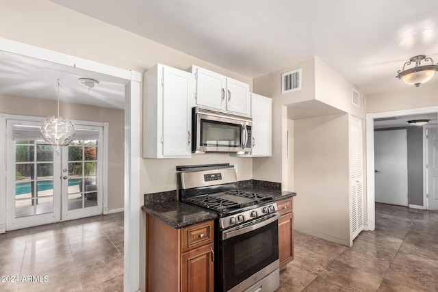 kitchen with white cabinetry, french doors, stainless steel appliances, dark stone counters, and decorative light fixtures