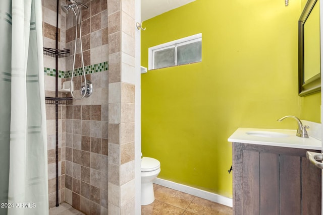 bathroom with tile patterned floors, vanity, tiled shower, and toilet