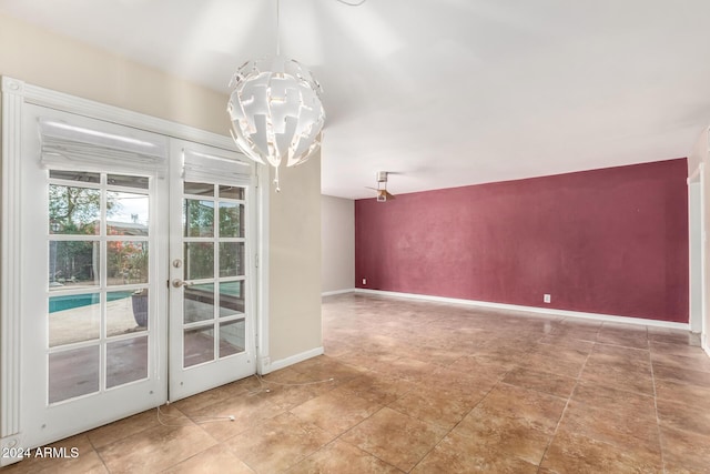 spare room featuring a notable chandelier and french doors