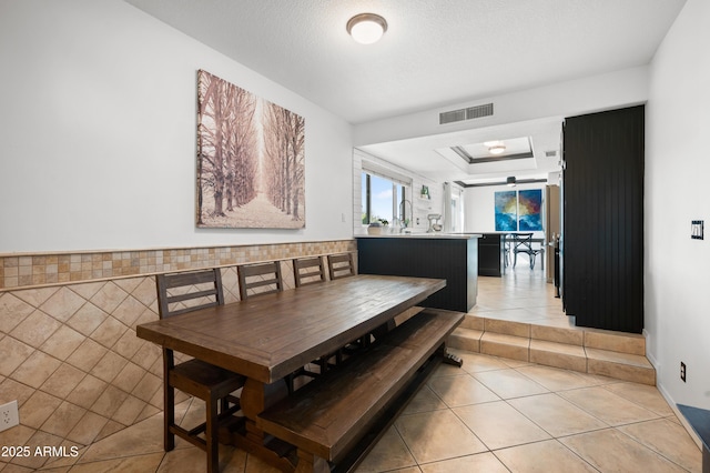 dining space featuring light tile patterned floors, sink, and a textured ceiling