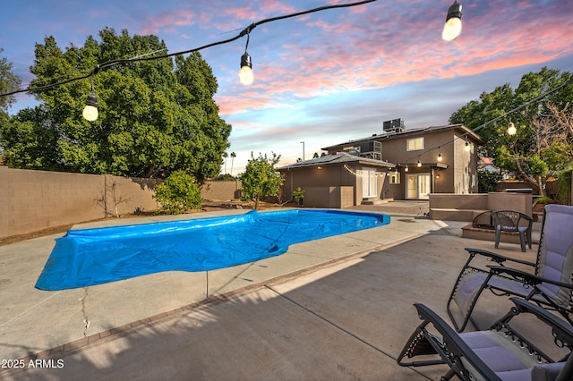 pool at dusk with a patio and central air condition unit