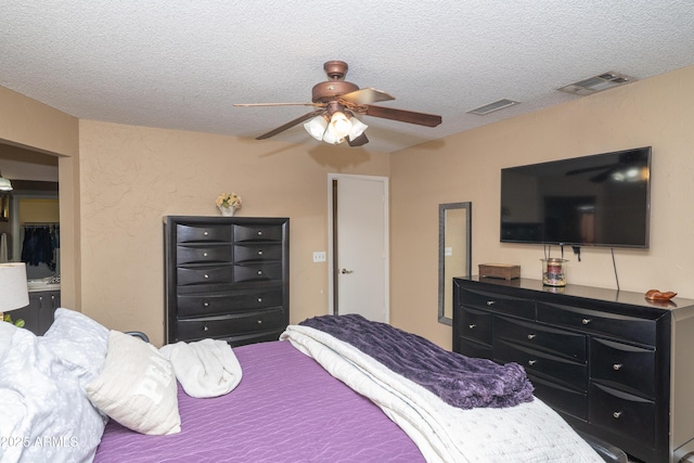 bedroom with a textured ceiling, visible vents, and a ceiling fan