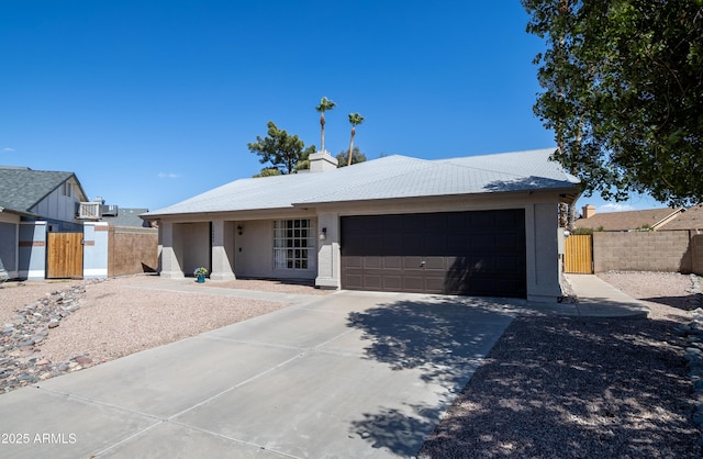 single story home with concrete driveway, an attached garage, fence, and a gate