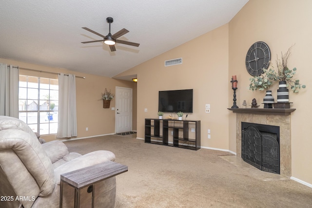 living area featuring visible vents, ceiling fan, a fireplace with flush hearth, carpet, and vaulted ceiling