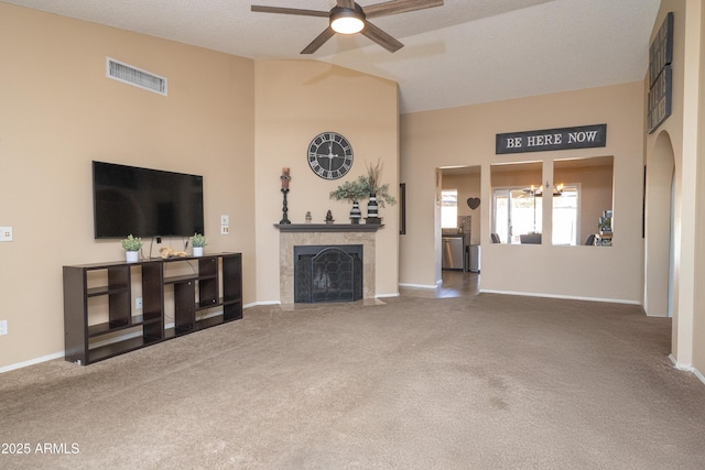 living area featuring carpet, a fireplace, visible vents, and ceiling fan with notable chandelier