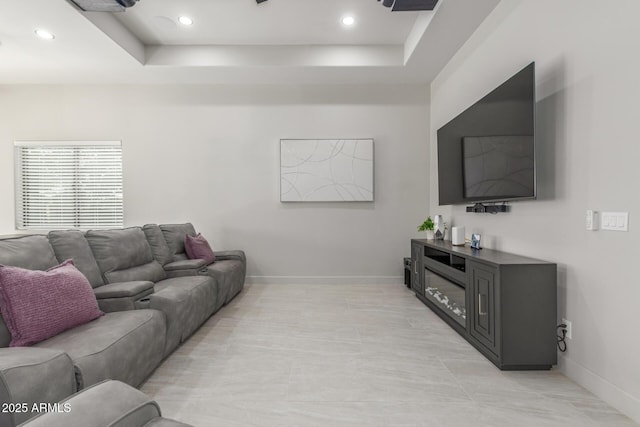 living room with a tray ceiling, recessed lighting, and baseboards