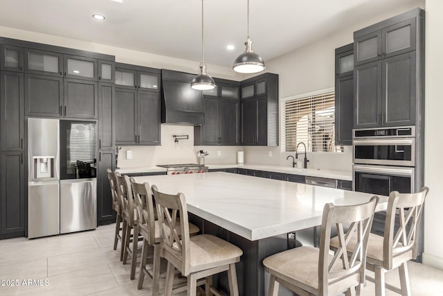 kitchen with appliances with stainless steel finishes, a center island, premium range hood, and glass insert cabinets