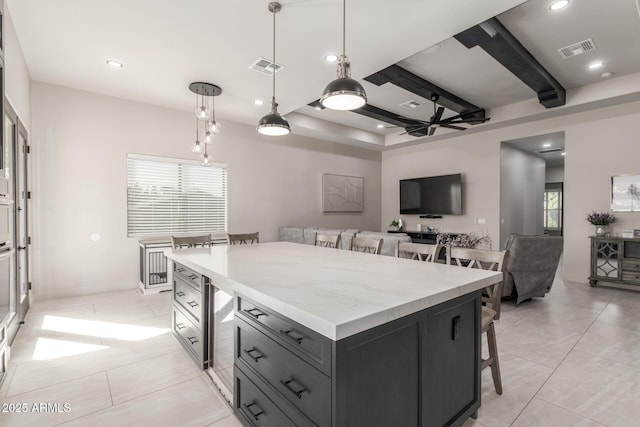 kitchen featuring visible vents, beamed ceiling, decorative light fixtures, and a kitchen breakfast bar