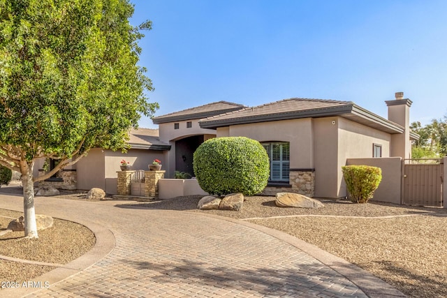 view of front of property with a gate, curved driveway, fence, and stucco siding