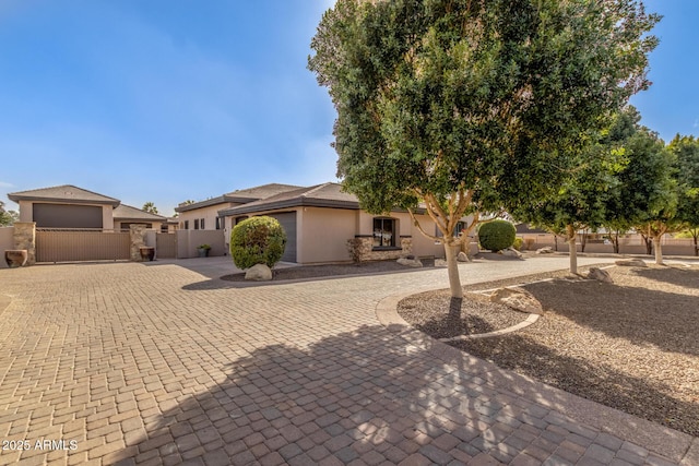 view of front of property with a gate, decorative driveway, fence, and stucco siding