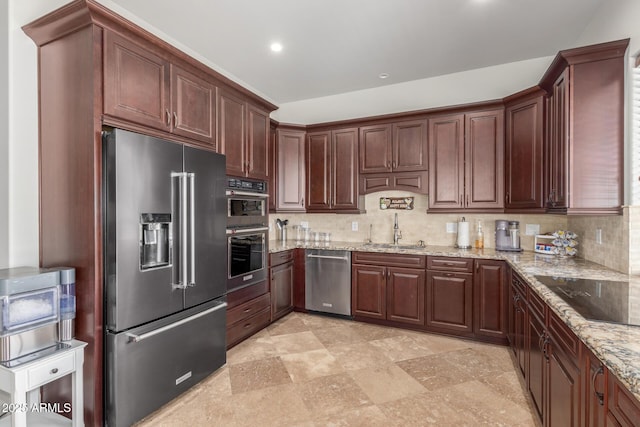 kitchen featuring decorative backsplash, light stone countertops, stainless steel appliances, a sink, and recessed lighting