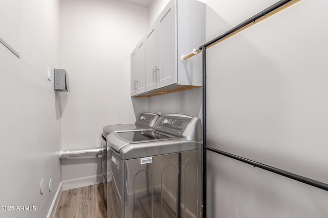 washroom featuring cabinet space, light wood-style flooring, baseboards, and independent washer and dryer