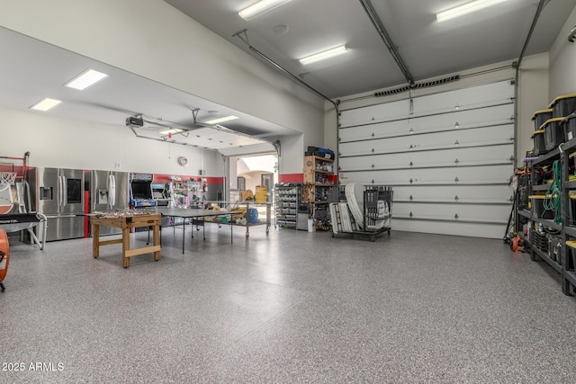 garage with stainless steel refrigerator with ice dispenser and a workshop area