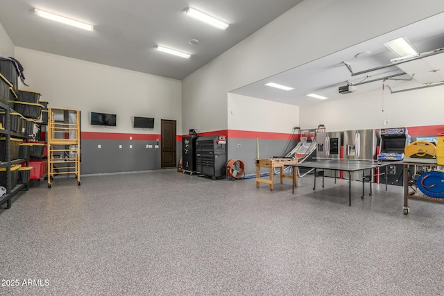 garage with stainless steel fridge and a garage door opener