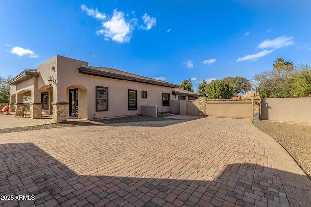 back of house featuring a patio, fence, a gate, and stucco siding