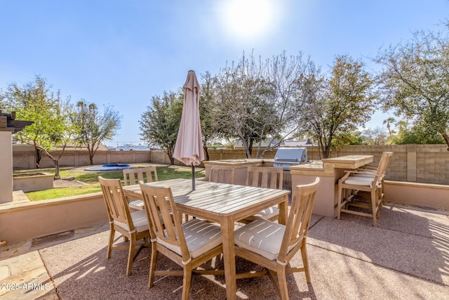 view of patio with a fenced backyard, a grill, outdoor dining area, and exterior kitchen