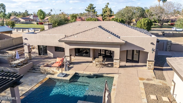 rear view of house with stucco siding, a tiled roof, and a patio