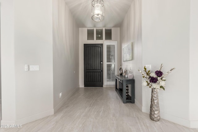 foyer entrance with a chandelier and baseboards