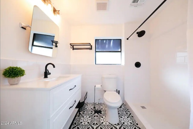 bathroom with tile patterned flooring, vanity, toilet, and walk in shower